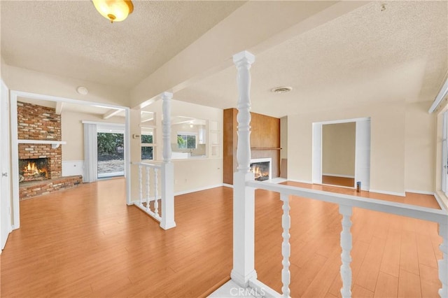 20468 College Blvd, Riverside, CA 92507 - interior space with a fireplace, a textured ceiling, wood finished floors, and decorative columns