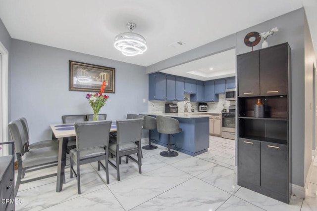 502 Holly Ave, Oxnard, CA 93036 - kitchen with light marble finish floors, stainless steel appliances, a peninsula, light countertops, and a breakfast bar area
