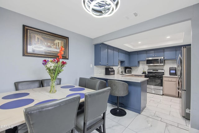 502 Holly Ave, Oxnard, CA 93036 - kitchen with stainless steel appliances, a peninsula, light countertops, blue cabinetry, and backsplash