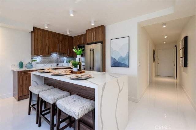 100 Scholz Plz Unit 205, Newport Beach, CA 92663 - kitchen featuring freestanding refrigerator, backsplash, a kitchen island, a kitchen breakfast bar, and light tile patterned floors