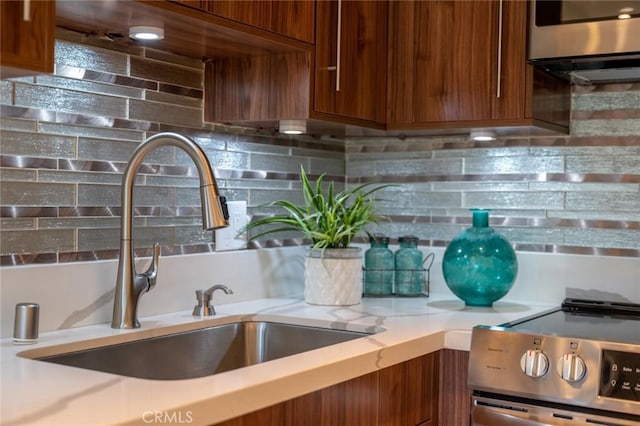 100 Scholz Plz Unit 205, Newport Beach, CA 92663 - kitchen featuring electric stove, light countertops, backsplash, and brown cabinets