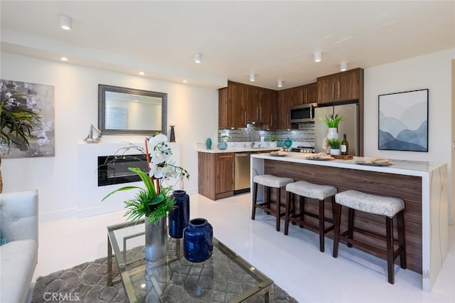 100 Scholz Plz Unit 205, Newport Beach, CA 92663 - kitchen featuring stainless steel appliances, a breakfast bar, light countertops, decorative backsplash, and recessed lighting
