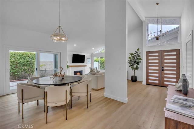 20441 Whitetree Cir, Huntington Beach, CA 92646 - dining area featuring a chandelier, high vaulted ceiling, light wood-type flooring, a lit fireplace, and recessed lighting