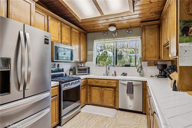 7050 Shale Rock Rd, Paso Robles, CA 93446 - kitchen featuring stainless steel appliances, wood ceiling, brown cabinetry, tile counters, and backsplash