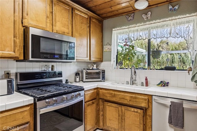 7050 Shale Rock Rd, Paso Robles, CA 93446 - kitchen with appliances with stainless steel finishes, wood ceiling, brown cabinetry, tasteful backsplash, and tile countertops