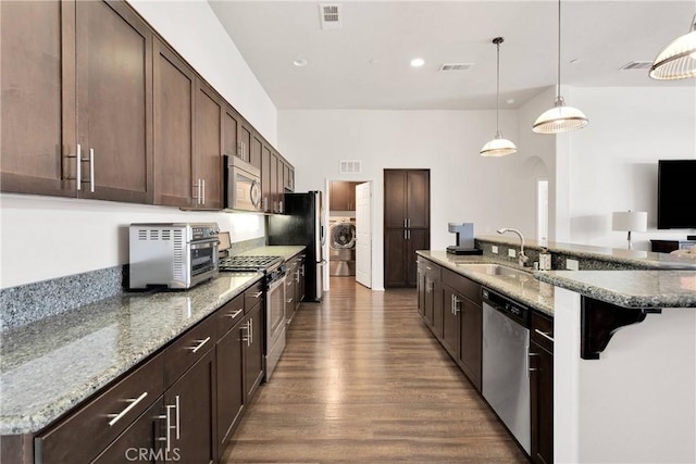 15558 Lookout Rd, Apple Valley, CA 92307 - kitchen featuring appliances with stainless steel finishes, washer / clothes dryer, dark wood-style flooring, dark brown cabinets, and a kitchen breakfast bar