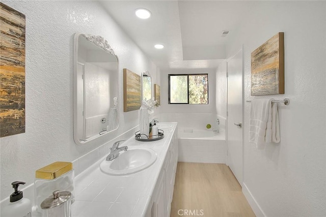 1207 Porto Grande Unit 1, Diamond Bar, CA 91765 - full bath featuring wood finished floors, a garden tub, double vanity, a textured wall, and recessed lighting