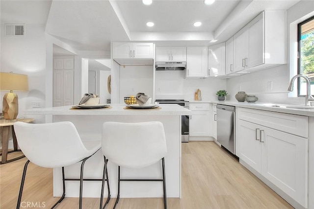 1207 Porto Grande Unit 1, Diamond Bar, CA 91765 - kitchen featuring stainless steel appliances, under cabinet range hood, white cabinetry, a breakfast bar, and recessed lighting
