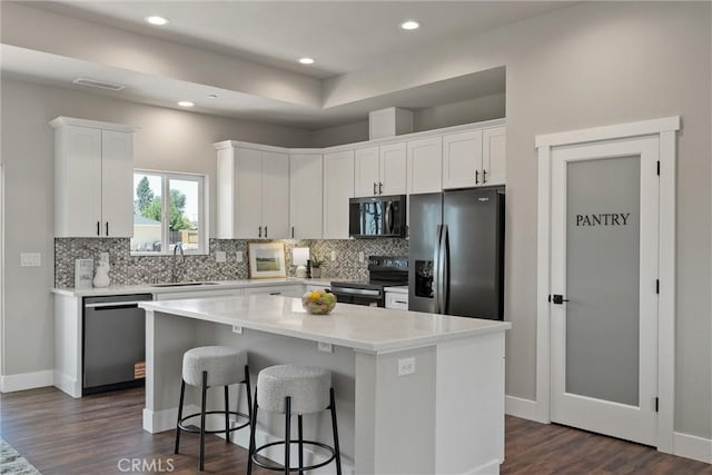 6169 Fern Ln, Paradise, CA 95969 - kitchen with stainless steel appliances, white cabinetry, tasteful backsplash, a center island, and dark wood-type flooring