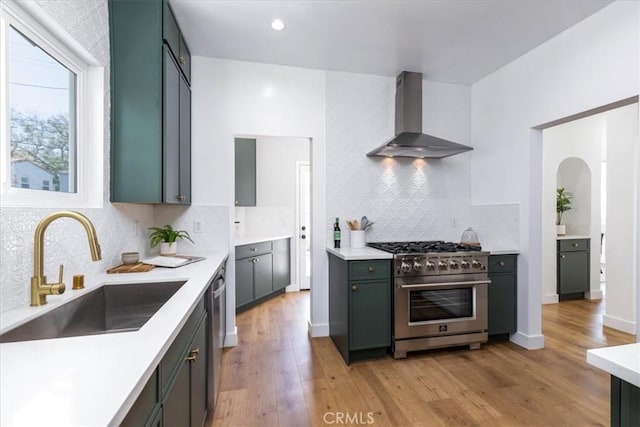4325 9th Ave, Los Angeles, CA 90008 - kitchen with appliances with stainless steel finishes, wall chimney exhaust hood, light wood-style flooring, decorative backsplash, and recessed lighting