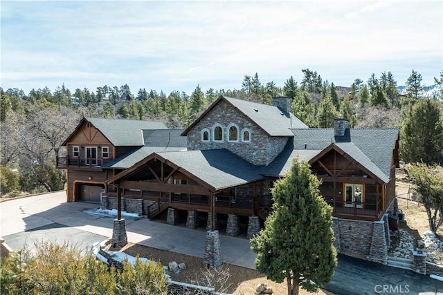 858 Fox Tower Way, Big Bear Lake, CA 92314 - back of house featuring stone siding, an attached garage, concrete driveway, a chimney, and roof with shingles