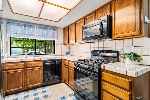 37229 Dalzell St, Palmdale, CA 93550 - kitchen with black appliances, brown cabinetry, and tasteful backsplash