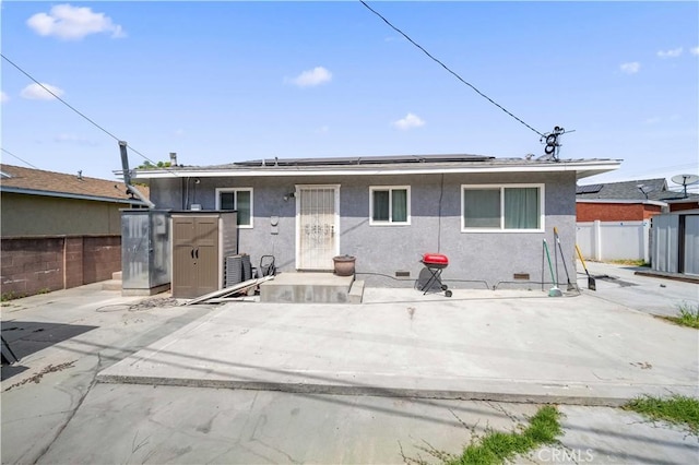 6838 Severn Dr, Paramount, CA 90723 - back of house with roof mounted solar panels, stucco siding, crawl space, and a storage unit