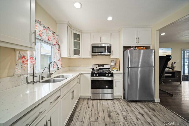6838 Severn Dr, Paramount, CA 90723 - kitchen featuring appliances with stainless steel finishes, healthy amount of natural light, light wood-type flooring, white cabinets, and recessed lighting