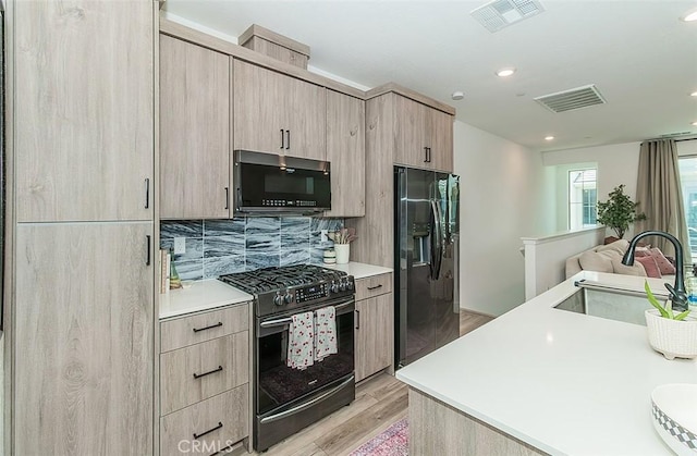 2887 E Tamarind Dr, Fresno, CA 93730 - kitchen with gas range, fridge with ice dispenser, light wood-style flooring, light countertops, and decorative backsplash