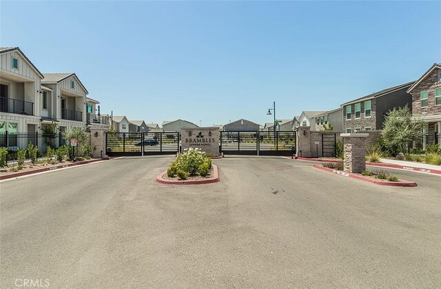 2887 E Tamarind Dr, Fresno, CA 93730 - view of asphalt road featuring a residential view, a gate, a gated entry, and curbs