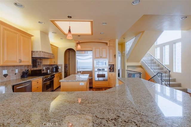 325 Juanita Ave, Oceano, CA 93445 - kitchen with built in appliances, custom exhaust hood, tasteful backsplash, light stone counters, and arched walkways