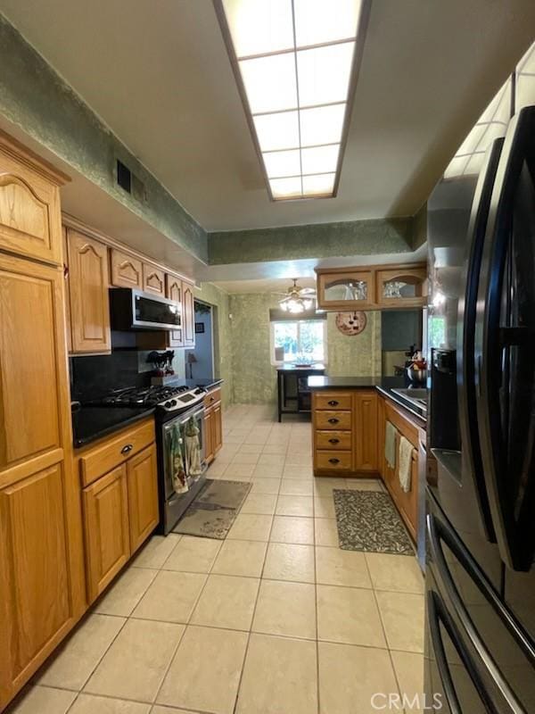 7430 Leucite Ave, Rancho Cucamonga, CA 91730 - kitchen featuring stainless steel appliances, light tile patterned floors, dark countertops, brown cabinets, and a peninsula