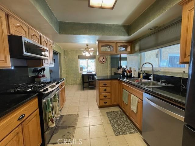 7430 Leucite Ave, Rancho Cucamonga, CA 91730 - kitchen with appliances with stainless steel finishes, light tile patterned flooring, brown cabinetry, and a peninsula