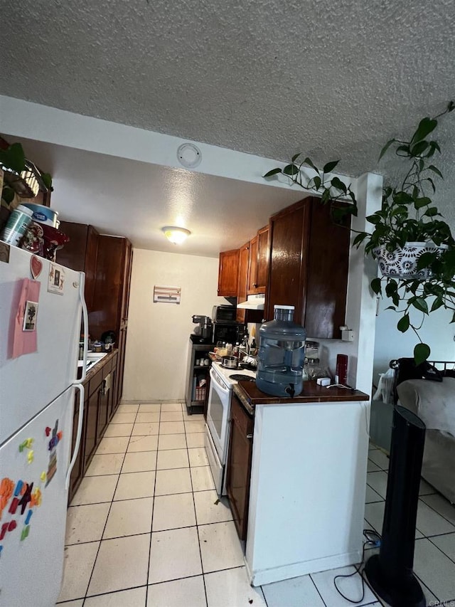 4139 46th St, San Diego, CA 92105 - kitchen featuring white appliances, a textured ceiling, light tile patterned floors, dark countertops, and under cabinet range hood