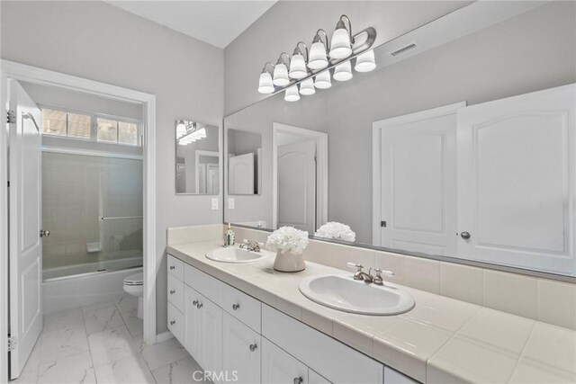 20704 Campania Ln, Porter Ranch, CA 91326 - bathroom featuring double vanity, marble look tiles, and enclosed tub / shower combo