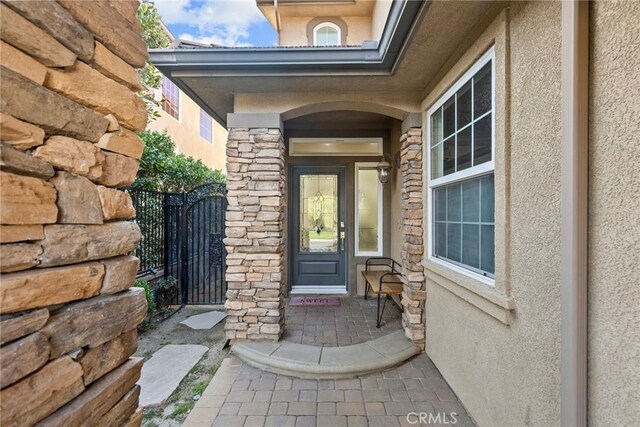 20704 Campania Ln, Porter Ranch, CA 91326 - view of exterior entry with stucco siding, stone siding, and a gate