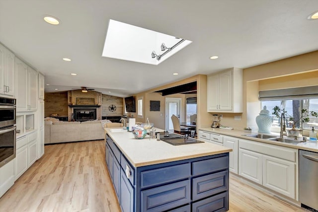 36485 Carney Rd, Valley Center, CA 92082 - kitchen featuring black electric cooktop, dishwasher, a skylight, blue cabinetry, and white cabinetry
