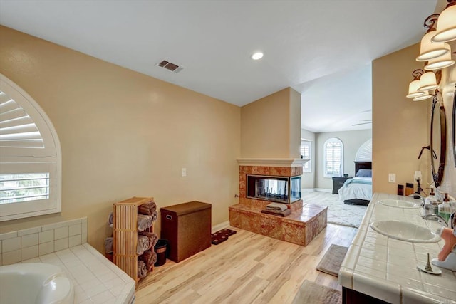 36485 Carney Rd, Valley Center, CA 92082 - full bathroom featuring double vanity, wood finished floors, a bath, connected bathroom, and a fireplace