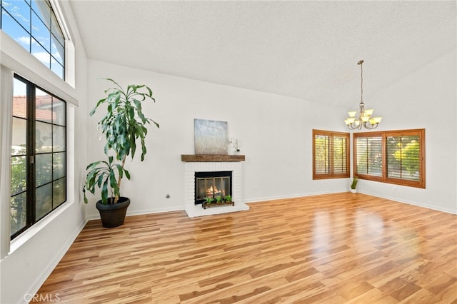 45857 Jeronimo St, Temecula, CA 92592 - unfurnished living room featuring light wood-style floors, a chandelier, a brick fireplace, and a high ceiling
