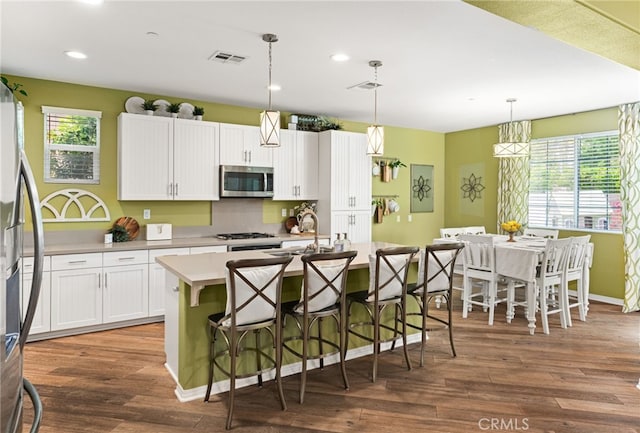 1568 Patterson Ranch Rd, Redlands, CA 92374 - kitchen featuring stainless steel appliances, light countertops, wood finished floors, white cabinetry, and a breakfast bar area