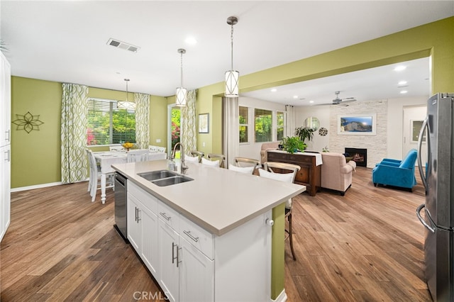 1568 Patterson Ranch Rd, Redlands, CA 92374 - kitchen featuring appliances with stainless steel finishes, wood finished floors, white cabinetry, a stone fireplace, and ceiling fan