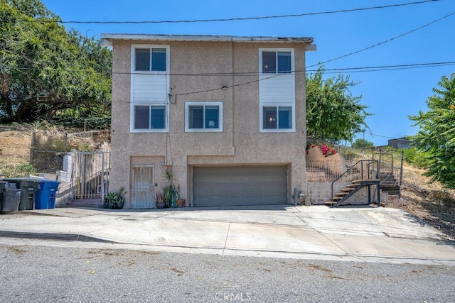 1134 N Rowan Ave, East Los Angeles, CA 90063 - view of front property with stairs, stucco siding, an attached garage, and driveway