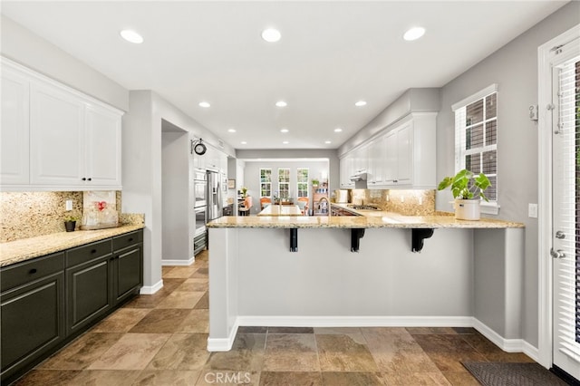 46287 Durango Dr, Temecula, CA 92592 - kitchen featuring white cabinets, a kitchen bar, tasteful backsplash, a peninsula, and recessed lighting
