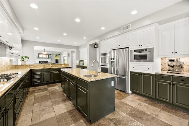 46287 Durango Dr, Temecula, CA 92592 - kitchen featuring appliances with stainless steel finishes, white cabinetry, decorative backsplash, an island with sink, and recessed lighting