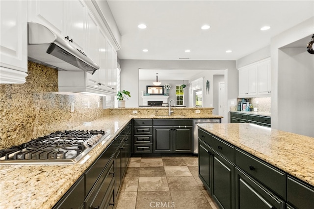 46287 Durango Dr, Temecula, CA 92592 - kitchen with under cabinet range hood, appliances with stainless steel finishes, white cabinetry, decorative backsplash, and light stone countertops