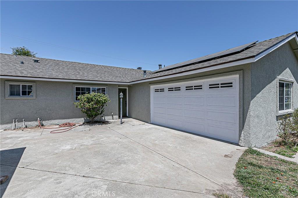 3963 Lobo Ln, Santa Maria, CA 93455 - ranch-style house with stucco siding, a garage, concrete driveway, and roof mounted solar panels