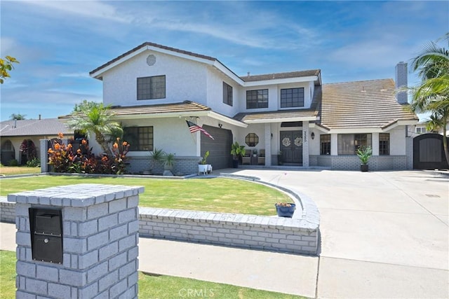 3380 E Date St, Brea, CA 92823 - view of front of house featuring an attached garage, driveway, stucco siding, a front yard, and brick siding
