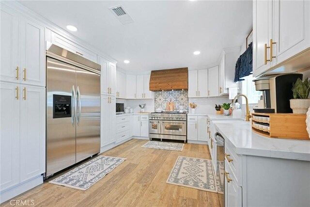 3380 E Date St, Brea, CA 92823 - kitchen featuring high end appliances, custom range hood, recessed lighting, white cabinetry, and light wood finished floors