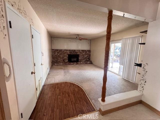 3246 Shamrock Ave, Merced, CA 95340 - unfurnished living room featuring ceiling fan, carpet floors, a fireplace, and a textured ceiling