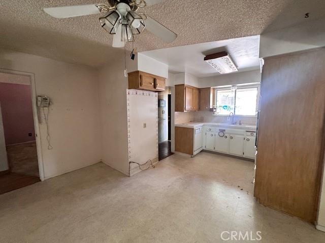 3246 Shamrock Ave, Merced, CA 95340 - kitchen with ceiling fan, light countertops, a textured ceiling, brown cabinets, and light flooring