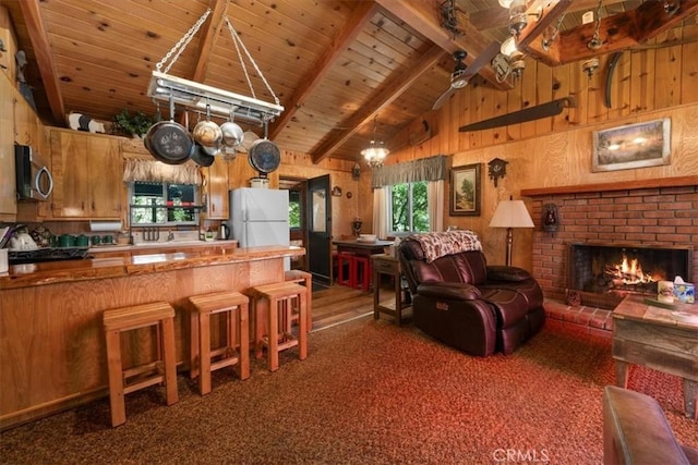 33019 Juniper Ln, Green Valley Lake, CA 92341 - kitchen featuring freestanding refrigerator, a wood ceiling with exposed beams, stainless steel microwave, a fireplace, and wood walls