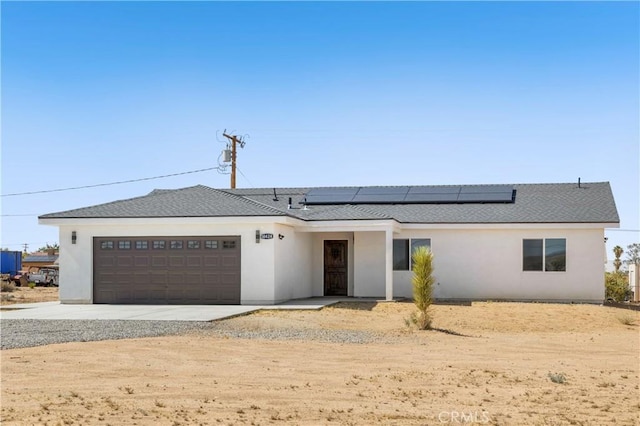 58424 Canterbury St, Yucca Valley, CA 92284 - view of front of house featuring driveway, an attached garage, stucco siding, and roof mounted solar panels