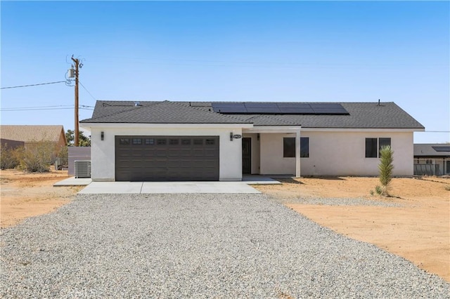 58424 Canterbury St, Yucca Valley, CA 92284 - view of front facade with gravel driveway, an attached garage, stucco siding, and solar panels