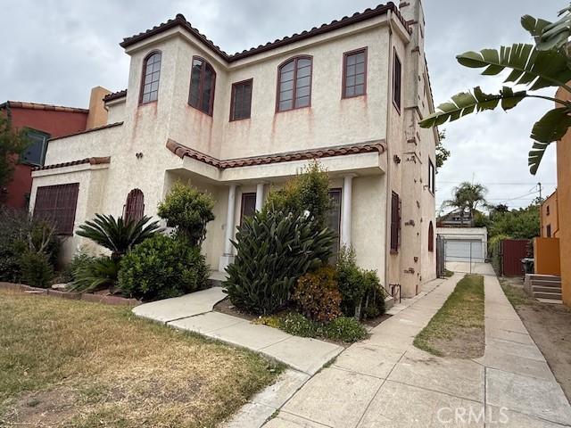 918 S Muirfield Rd, Los Angeles, CA 90019 - view of front of house with stucco siding, concrete driveway, a tiled roof, and a garage