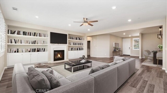 5120 Armendarez Ln, Fontana, CA 92336 - living area featuring ceiling fan, wood finished floors, a glass covered fireplace, recessed lighting, and built in shelves
