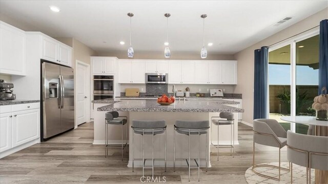 5120 Armendarez Ln, Fontana, CA 92336 - kitchen with stainless steel appliances, light wood finished floors, recessed lighting, white cabinets, and a kitchen breakfast bar