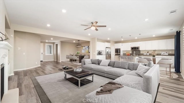 5120 Armendarez Ln, Fontana, CA 92336 - living room with light wood-style flooring, ceiling fan, recessed lighting, and a fireplace
