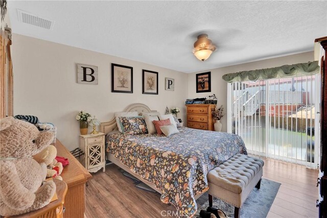 26460 Gem Ct, Helendale, CA 92342 - bedroom with access to exterior, wood finished floors, and a textured ceiling