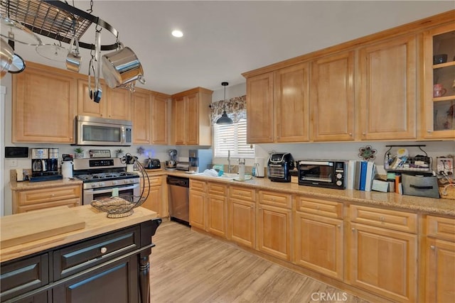 26460 Gem Ct, Helendale, CA 92342 - kitchen featuring appliances with stainless steel finishes, light wood-style flooring, hanging light fixtures, light brown cabinets, and glass insert cabinets
