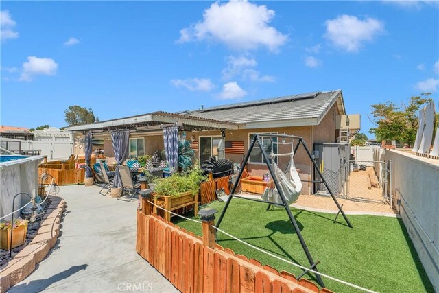 26460 Gem Ct, Helendale, CA 92342 - back of house featuring a fenced backyard, roof mounted solar panels, a gate, a patio, and stucco siding